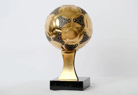 Ballon d'or récompensant le meilleur joueur de la Coupe du Monde de football en 1986 au Mexique, et remporté par Diego Maradona, alliage cuivreux doré, h. 28 cm. © Aguttes / Yann Vernerie